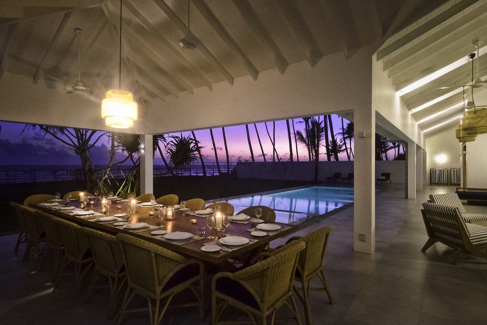 The long dining table lit by candles at dusk