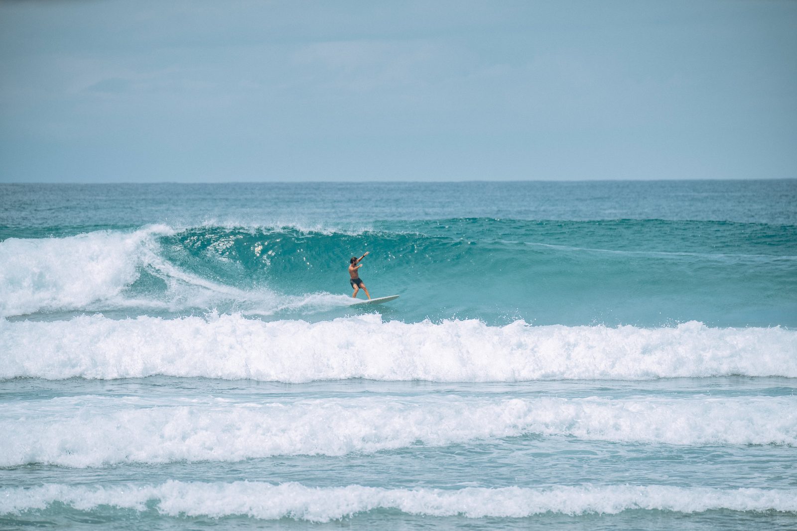 A surfer riding a clean wave at sunset